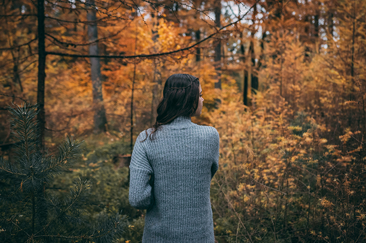 Woman walking on a trail through the foliage.